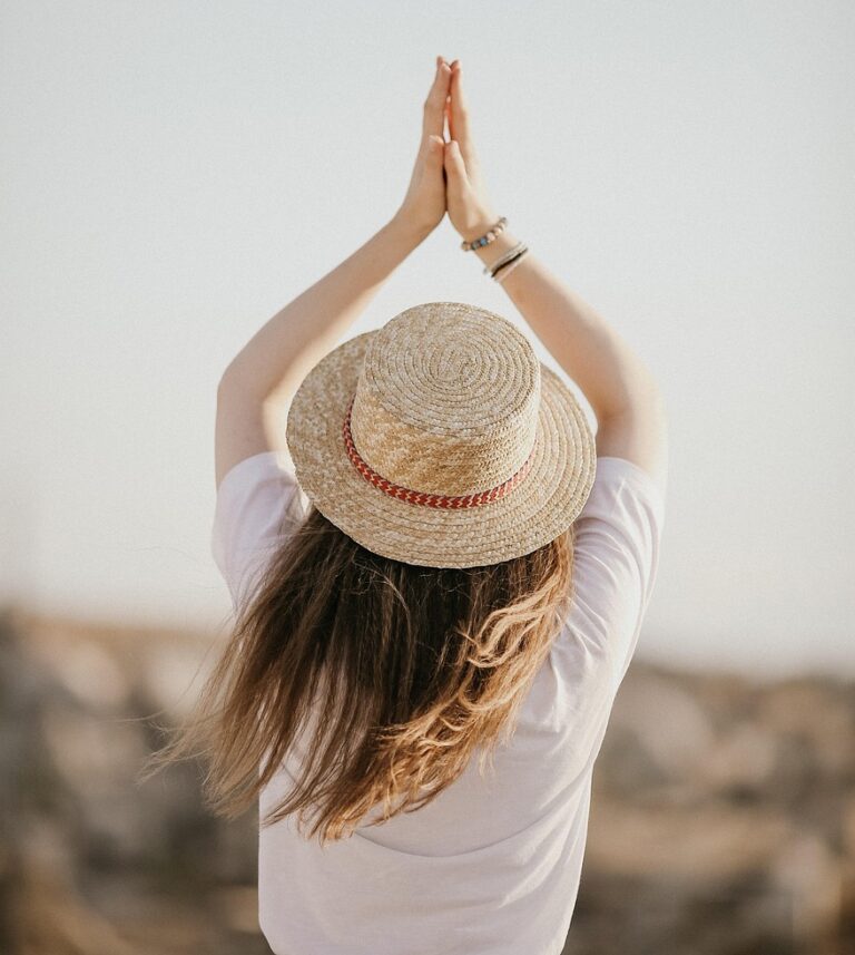 Une personne de dos les mains jointes au dessus de la tête dans une posture inspirant énergie et équilibre